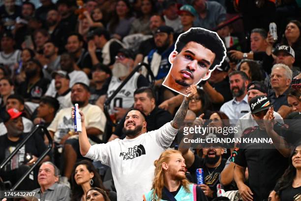 Fan holds a cutout with the face of San Antonio Spurs' French forward-center Victor Wembanyama during the NBA basketball game between the Dallas...