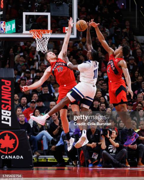 Naz Reid of the Minnesota Timberwolves is blocked at the net by Jakob Poeltl and Scottie Barnes of the Toronto Raptors during the second half of...