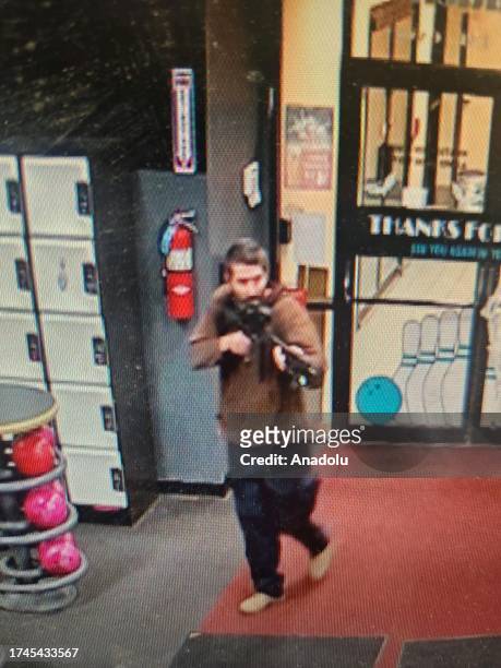 Man with a gun walks on the street after shoot civil in Maine, United States on October 26, 2023. At least 22 people were killed in shootings at...