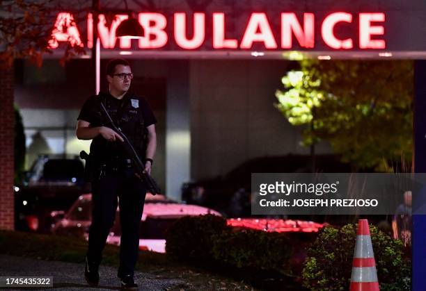 An armed police officer guards the ambulance entrance to the Central Maine Medical Center in Lewiston, Maine early on October 26, 2023. A massive...