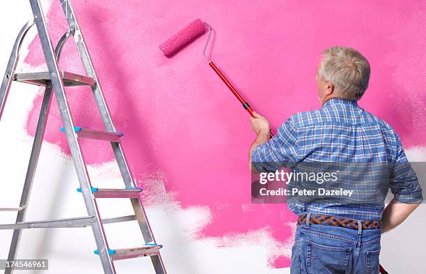 senior man painting wall in new home - man pink pants stock pictures, royalty-free photos & images