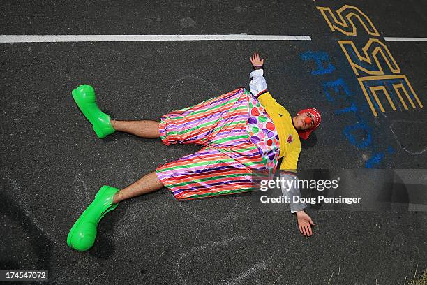 Fan dressed as a clown lies in the road during stage seventeen of the 2013 Tour de France, a 32KM Individual Time Trial from Embrun to Chorges, on...