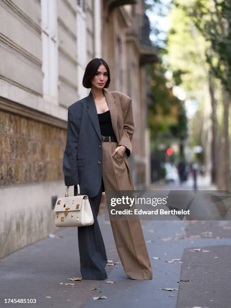 Heart Evangelista wears a bi-color gray and brown striped oversized blazer jacket, matching suit flared wide-leg pants, a low-neck black top, a...