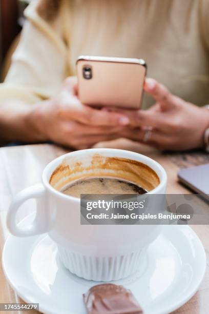 close-up of cup of coffee and in background some hands working with cell phone - coffee cup top view stockfoto's en -beelden