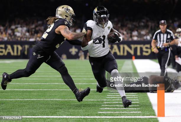 Travis Etienne Jr. #1 of the Jacksonville Jaguars scores a rushing touchdown during the second quarter as Tyrann Mathieu of the New Orleans Saints is...