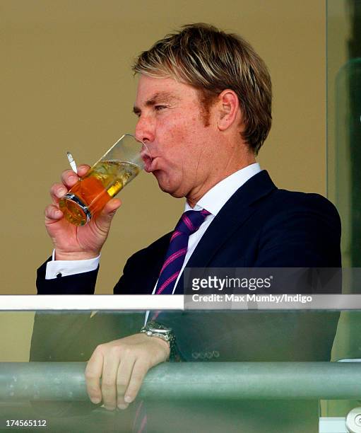 Shane Warne fools around with his glass of drink as he and Elizabeth Hurley attend the Betfair Weekend, featuring the King George VI and Queen...