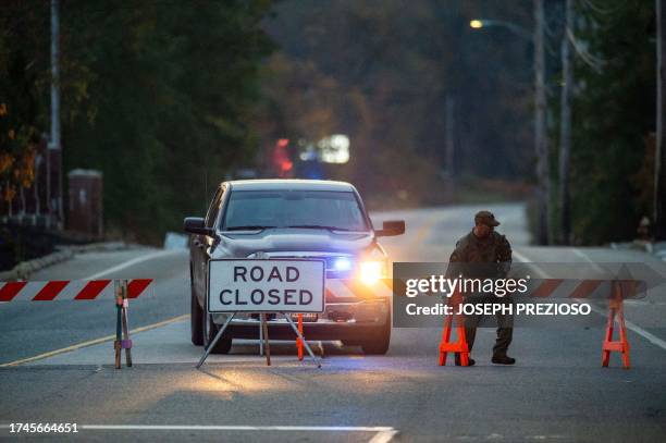 Law enforcement official moves a road block into place blocking the road to Schemengees Bar where a shooting took place yesterday in Lewiston, Maine...