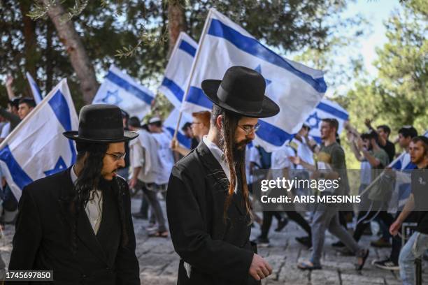 Two ultra Orthodox men walk past religious Israeli pre-military aged youth, wave their national flag as they protest outside the Old City of...