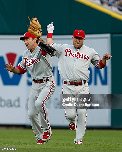 Right fielder Laynce Nix of the Philadelphia Phillies, right, collides with second baseman Chase Utley and looses his glove after Utley catches a fly...