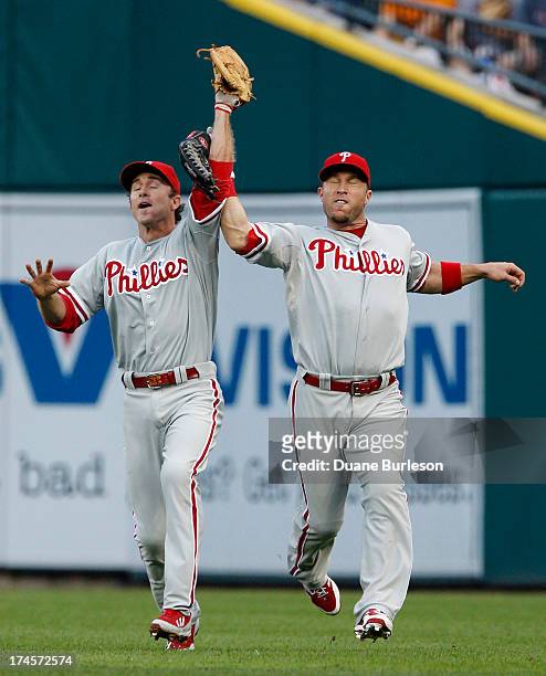 Right fielder Laynce Nix of the Philadelphia Phillies, right, collides with second baseman Chase Utley and looses his glove after Utley catches a fly...