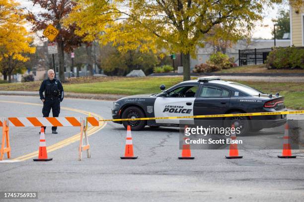 Police officer blocks access to the road to Sparetime Recreation on October 26, 2023 in Lewiston, Maine. Police are still searching for the suspect...