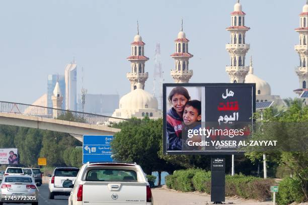 Cars drive past a billboard bearing a picture of Palestinian children and an inscription in Arabic that reads "Have you killed a Palestinian today ?...