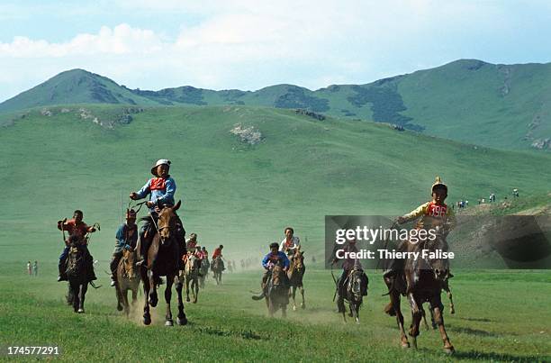 Mongolian child jockeys ride through the grasslands at a horserace during the Naadam festival. The young jockeys can ride up to 30 kilometers in the...