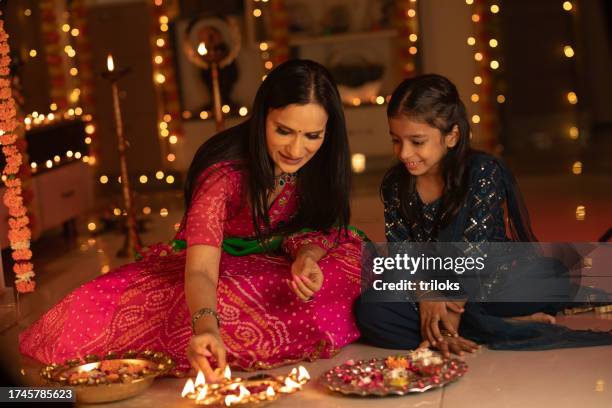 mother with daughter decorating plate at home - diwali stock pictures, royalty-free photos & images