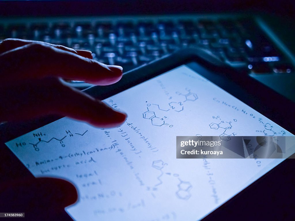 Woman touching chemical formula on digital tablet