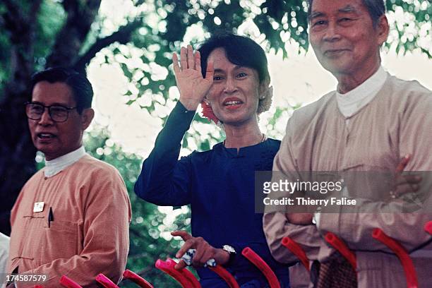 Burmese dissident and Nobel prize laureate Aung San Suu Kyi is addressing supporters gathered outside her home. At her side stand two leaders from...
