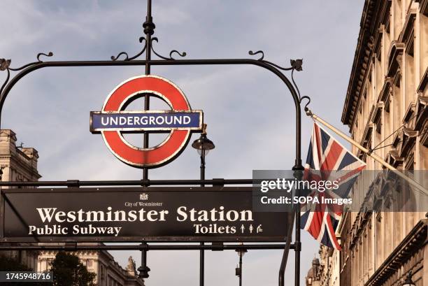 Iconic entrance to Westminster underground tube station with a British Union Jack flag flying in the background.