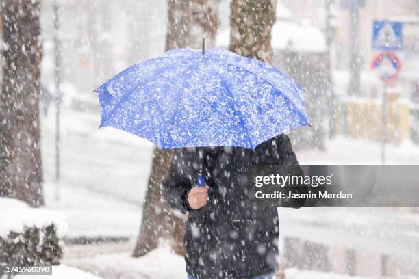 man with umbrella under snow on city street - 雪 ストックフォトと画像