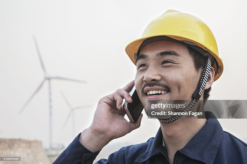 Worker on His Phone In Front of Windmills