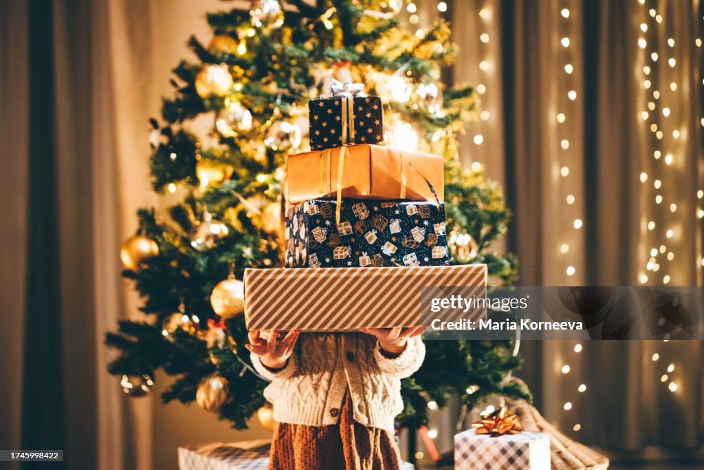 Girl holding stack of Christmas presents.