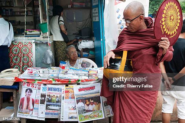 Buddhist monk walks past a newsstand selling newspapers showing pictures of Aung San Suu Kyi..