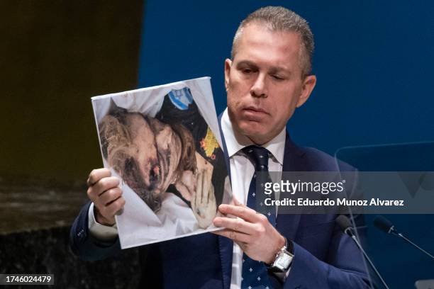 Permanent Representative of Israel to the United Nations Gilad Erdan, show a picture of a Israeli woman killed by Hamas as he speaks at the General...