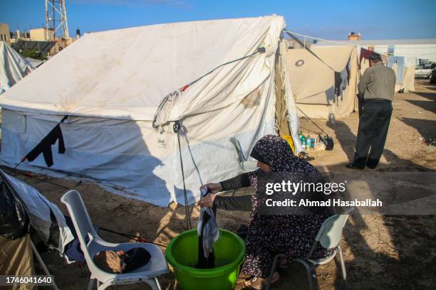 Palestinian woman does laundry outside a refugee tent along the Gaza Strip on October 20, 2023 in Khan Yunis, Gaza. Gazans are evacuating to the...