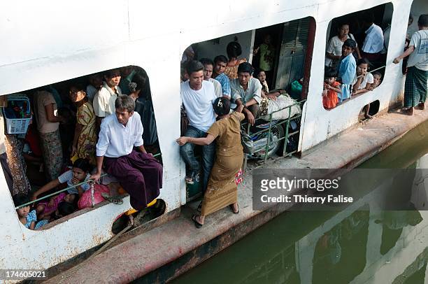 People go aboard a passenger boat on the Kaladan River in Mrauk U..