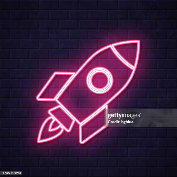 rocket. glowing neon icon on brick wall background - ship on fire stock illustrations