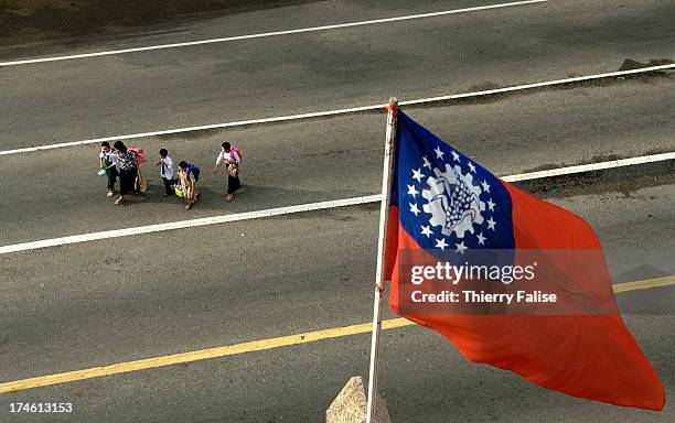 Group of children on their way to school walks under the Myanmar national flag on a Yangon street..