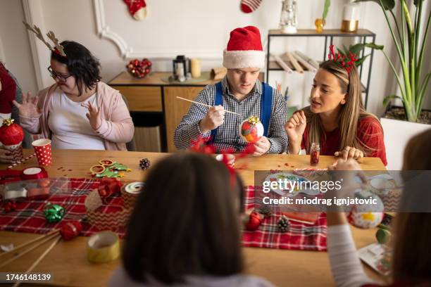 people with down syndrome decorating christmas ornaments with the help of their friends - christmas tree brush stock pictures, royalty-free photos & images