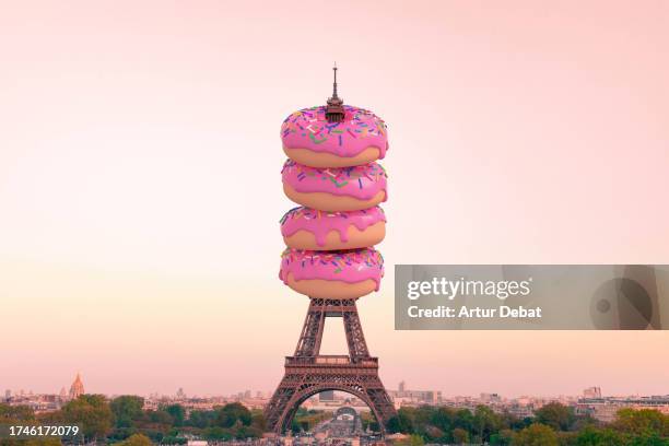 creative digital composition of the tour eiffel in paris with huge pink frosted doughnuts. - digital composite stock pictures, royalty-free photos & images