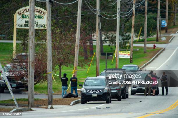 Law enforcement official embraces with a person outside Schemengees Bar where a mass shooting occurred yesterday in Lewiston, Maine on October 26,...