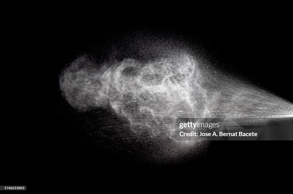 Pressurized water jet with a cloud of sprayed water drops on a black background.