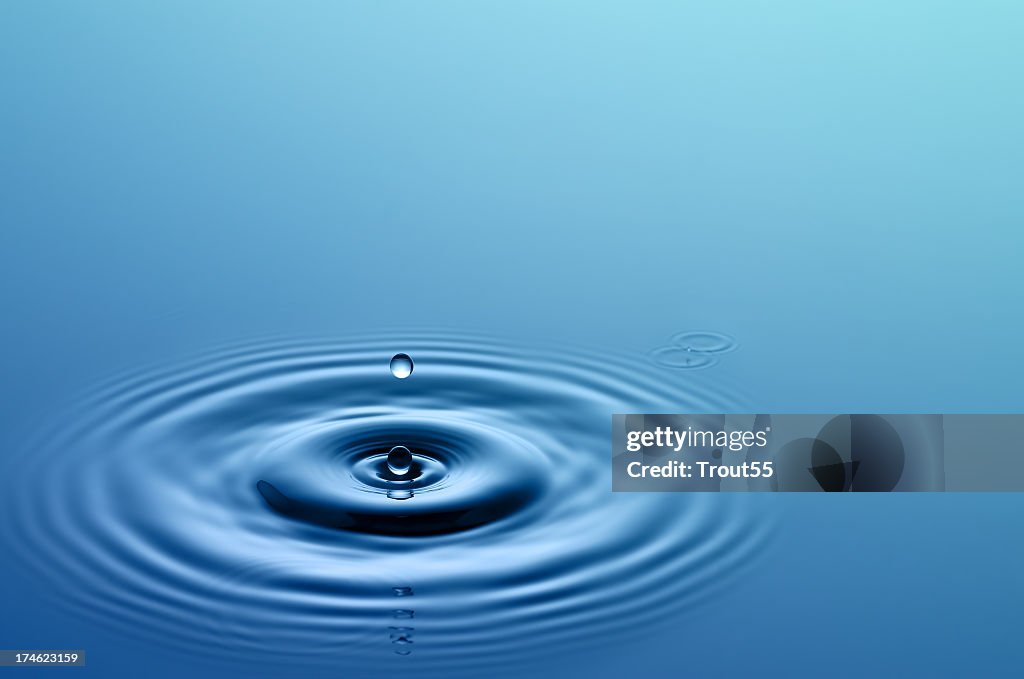 Single drop of water hitting a larger body of water