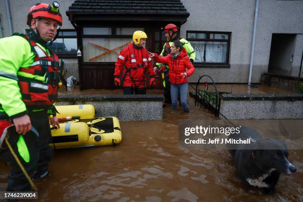 Members of the coastguard speak to a woman as they rescue her and her family from flood waters surrounding the houses on October 20, 2023 in Brechin...