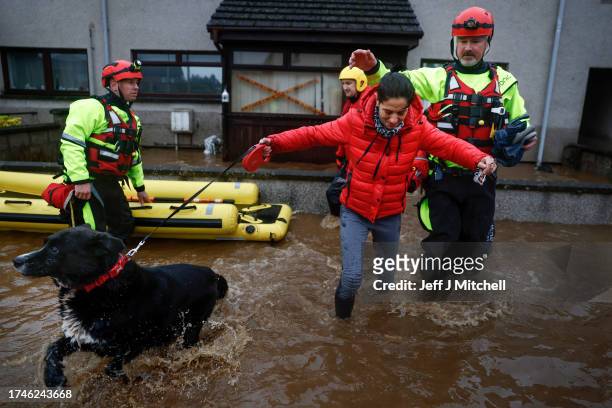 Members of the coastguard help a woman as they rescue her and her family from flood waters surrounding the houses on October 20, 2023 in Brechin...