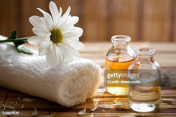 aroma therapy oils placed next to a white towel and flower - spa bildbanksfoton och bilder