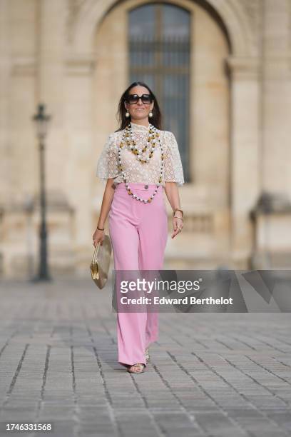 Alba Garavito Torre wears pearl earrings, a long/large pearl necklace, a cream guipure mesh embroidered blouse from Room 717, pink high rise and wide...