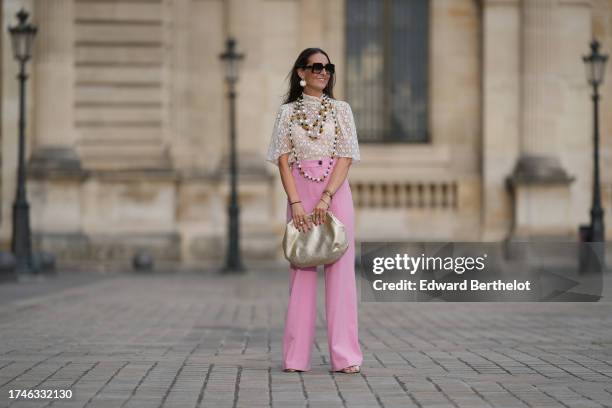 Alba Garavito Torre wears pearl earrings, a long/large pearl necklace, a cream guipure mesh embroidered blouse from Room 717, pink high rise and wide...