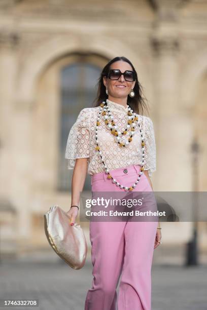 Alba Garavito Torre wears pearl earrings, a long/large pearl necklace, a cream guipure mesh embroidered blouse from Room 717, pink high rise and wide...