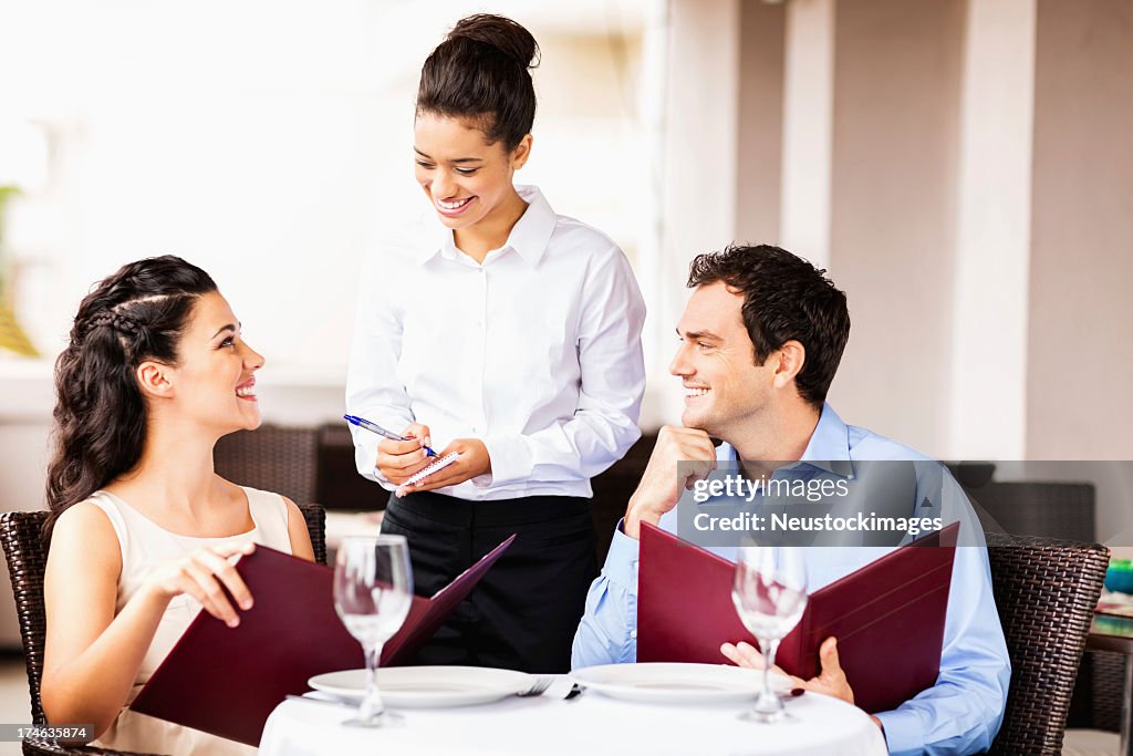 Waitress Taking Order From Couple At Restaurant