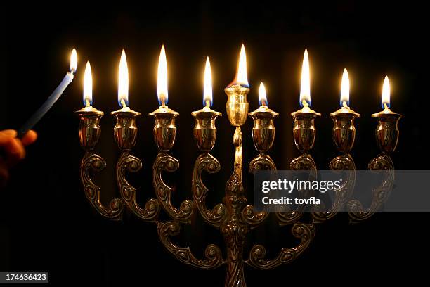 someone lighting the last candle of a menorah - chanoeka stockfoto's en -beelden