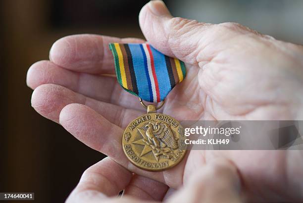 senior hand holding military metal. - military medal stock pictures, royalty-free photos & images