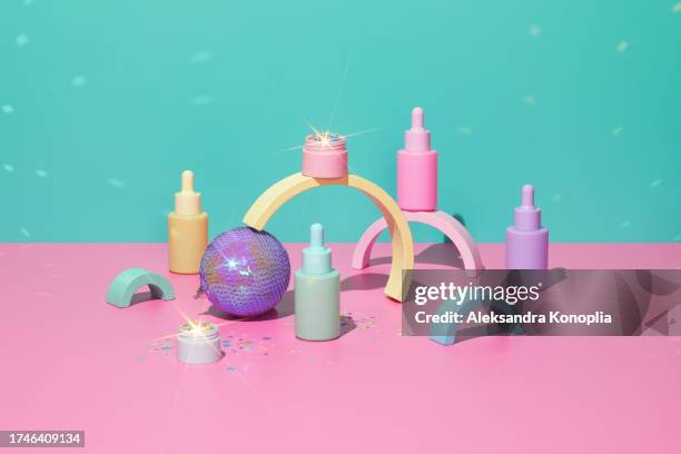 3d stage with set of cute kawaii pastel colorful cosmetics bottles and jar filled with shiny glitter on pink table with abstract geometric figures, holographic christmas ornaments and disco ball light spots on turquoise mint green background. - stage light 3d stock pictures, royalty-free photos & images