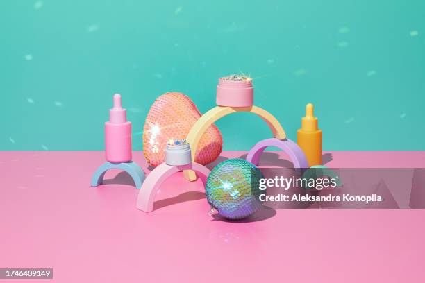 3d stage with set of cute kawaii pastel colorful cosmetics bottles and jar filled with shiny glitter on pink table with abstract geometric figures, holographic christmas ornaments and disco ball light spots on turquoise mint green background. - stage light 3d stock pictures, royalty-free photos & images