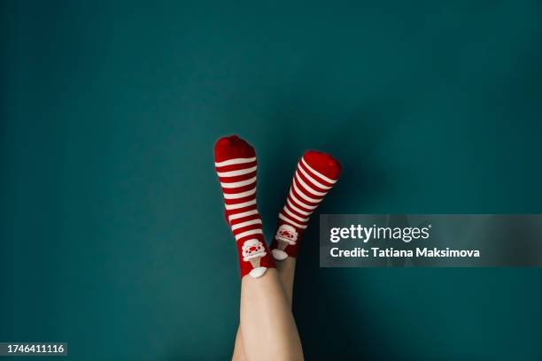 feet in christmas striped socks against a dark green wall. - striped socks stock pictures, royalty-free photos & images