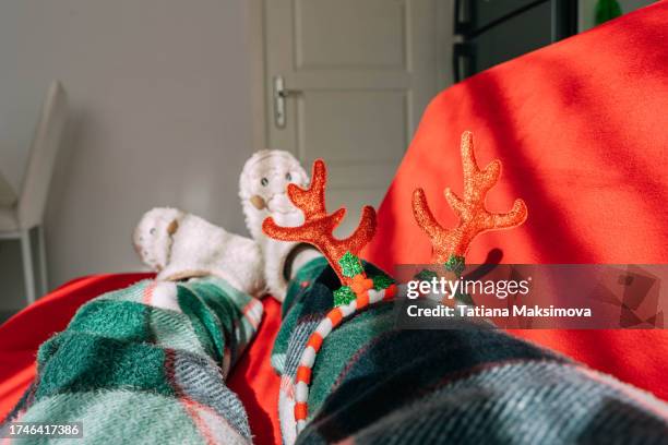 morning after christmas, hangover. a woman's legs in pajamas on a red couch and a glass of water in her hand. - pyjamas stock pictures, royalty-free photos & images