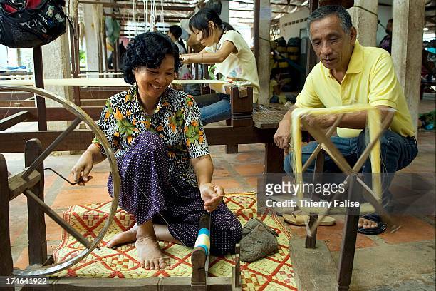 Morimoto Kikuo , a Japanese artist and founder of the Institute for Khmer Traditional Textiles in Siem Reap, chats with a woman who is reeling the...