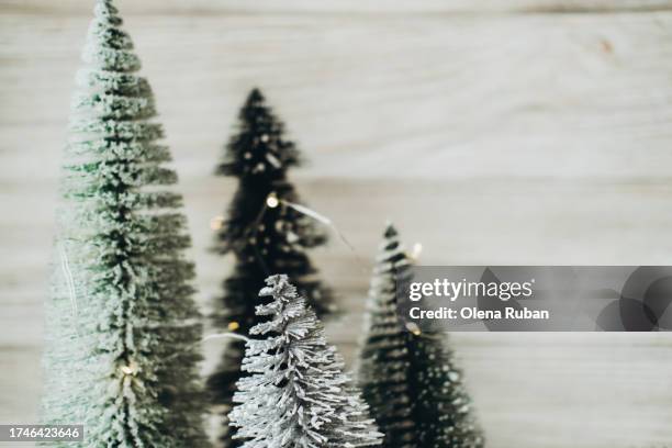 snowy christmas trees on stumps with led string garland against wooden wall. - led stumps stock pictures, royalty-free photos & images